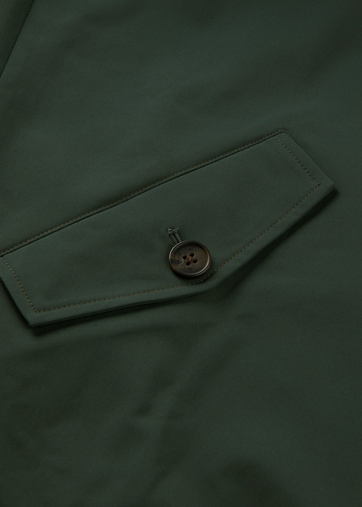 Close-up of a green pocket with flap and dark button on the Lakeward Men’s Reversible Bomber Jacket.