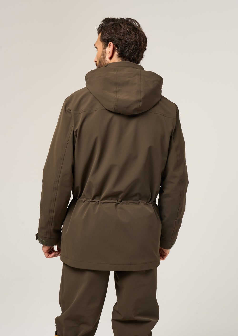 Man seen from the back in a Lockwood Men’s Shooting Coat in olive, shooting fit, against a plain light background.