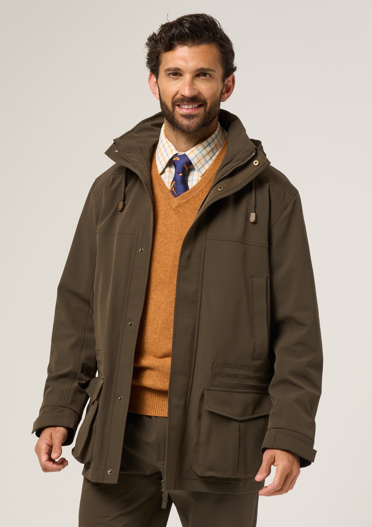 Man wearing Lockwood Men’s Shooting Coat in Olive, smiling against a plain background.