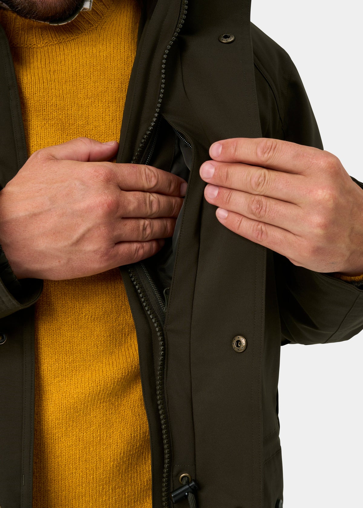 Man in yellow sweater opens inner pocket of Dunswell Men’s Waterproof Field Coat in Olive - Shooting Fit.