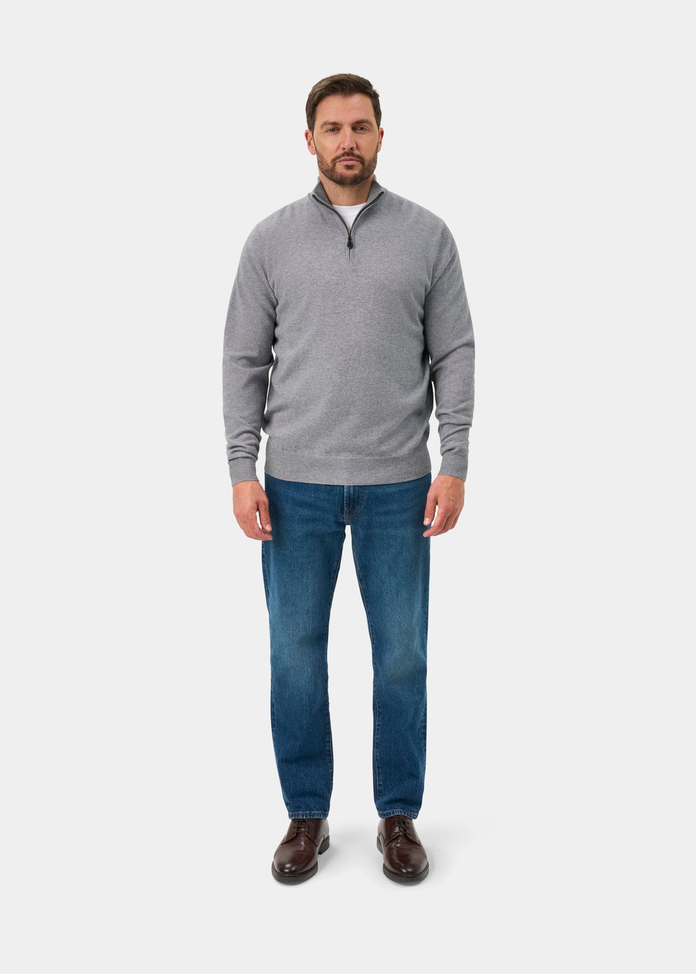 Man wears Hanbury Pure Cashmere Quarter Zip Jumper in Light Grey Mix, blue jeans, and brown shoes facing forward.