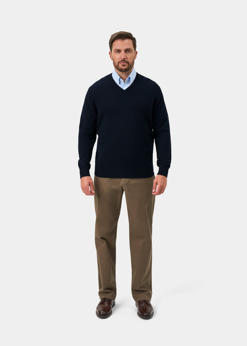 Man wearing Haddington Pure Cashmere V-Neck Jumper in Dark Navy, light blue shirt, khaki pants, and brown shoes.