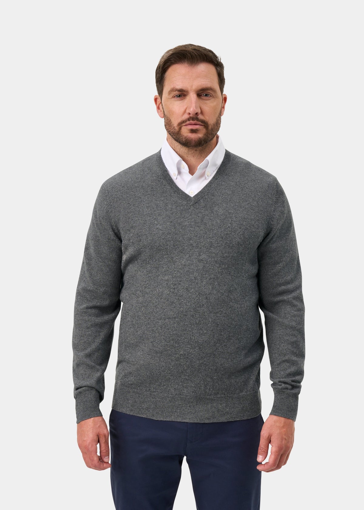 Man in Haddington Pure Cashmere V-Neck Jumper (Derby, Regular Fit) over white shirt and navy pants, plain background.