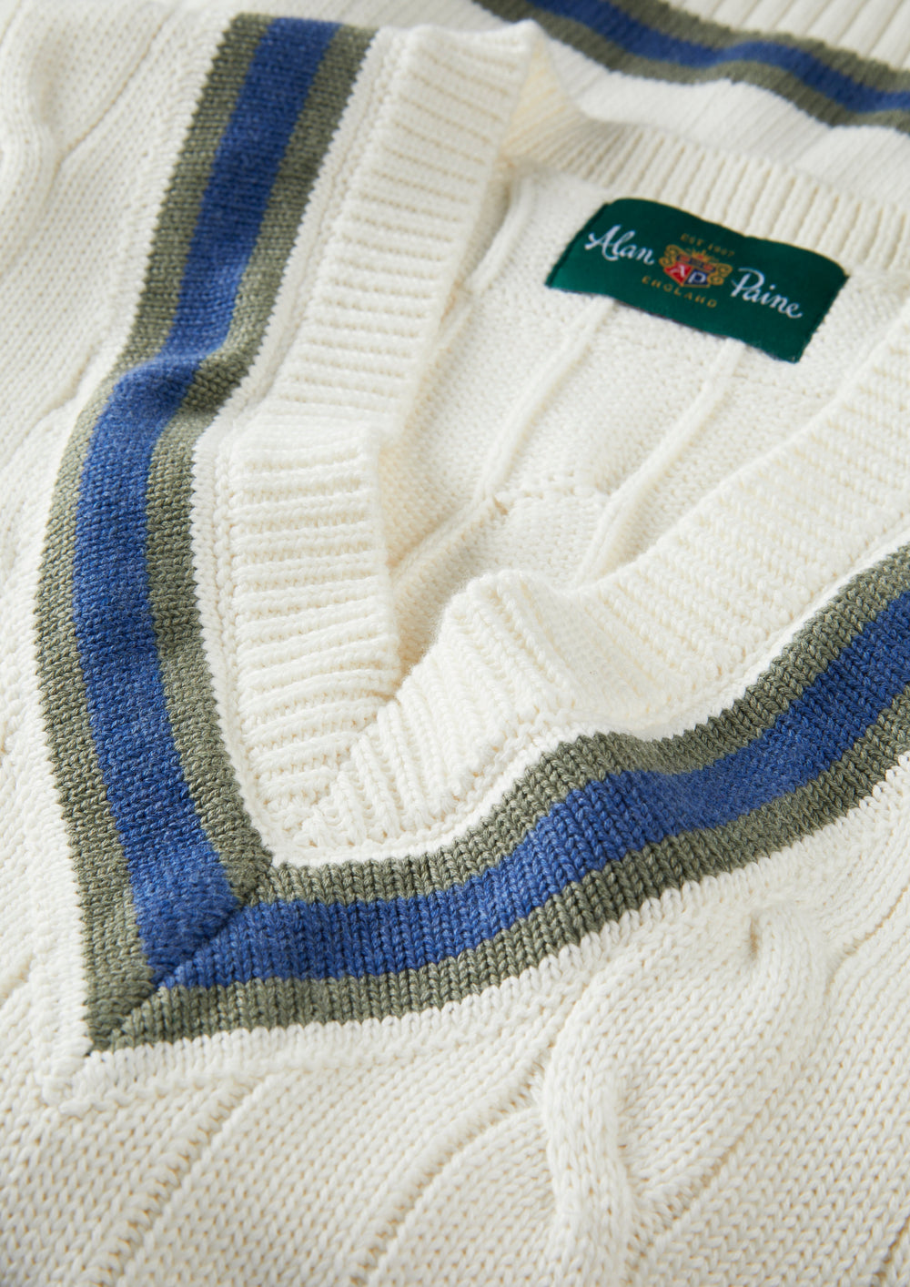 Close-up of Chadbury cotton cable knit cricket slipover in ecru/landscape with striped V-neck and green label.
