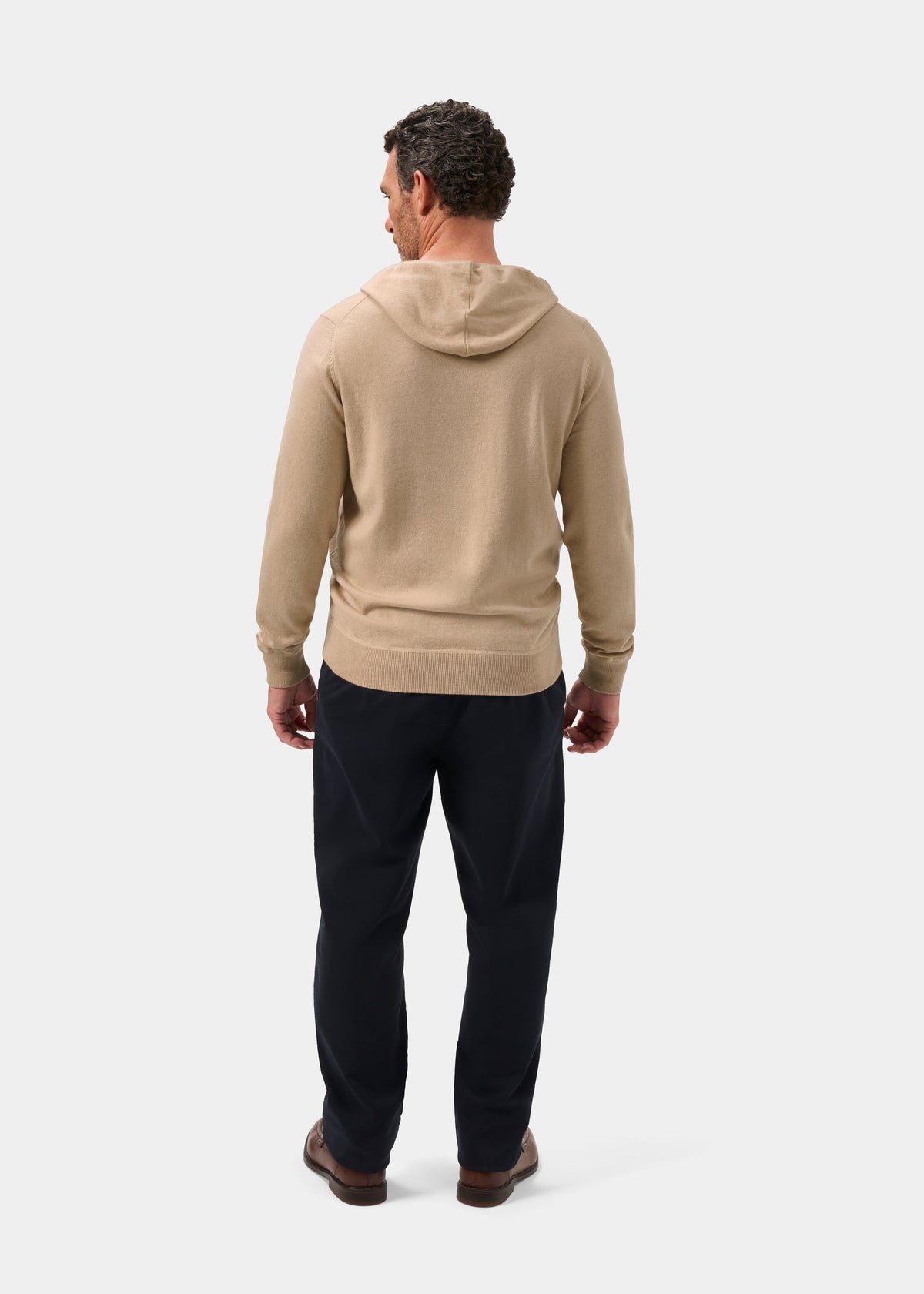 Man facing away in Gaisby Cotton Merino Hoodie in Oatmeal - Regular Fit, dark pants, brown shoes, plain background.