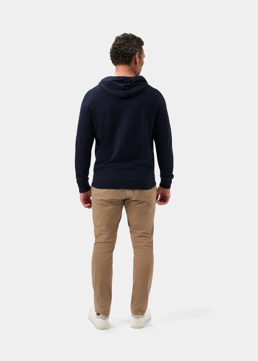 Man facing away in Gaisby Cotton Merino Hoodie in Dark Navy, khaki pants, and white shoes on white background.