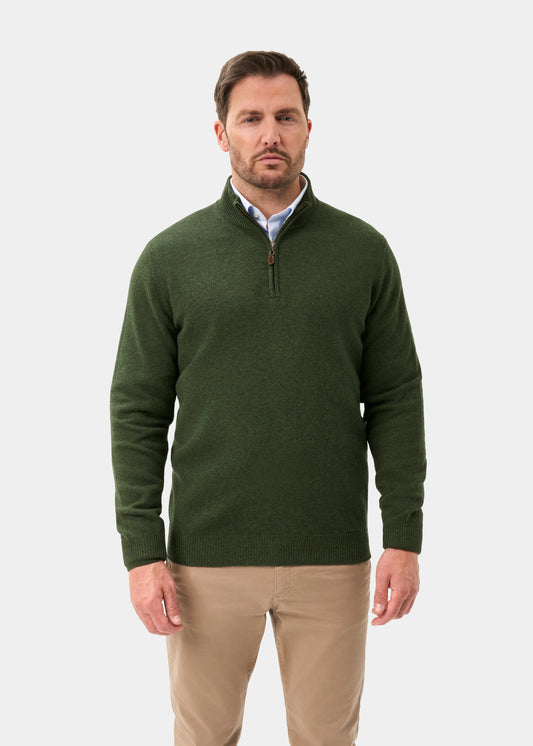 A man wears a Sutherland Lambswool Quarter Zip Jumper In Rosemary over a light blue collared shirt and tan trousers.