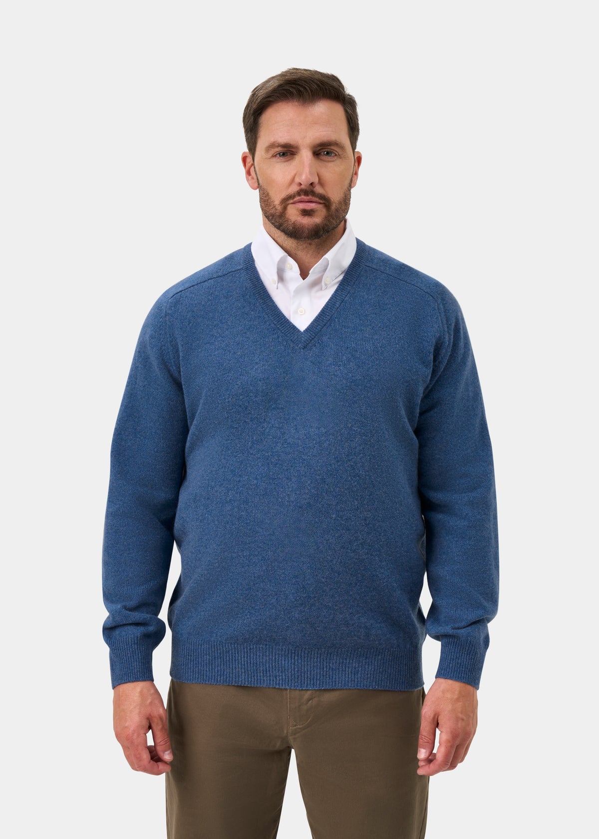 Man in a Hampshire Lambswool Vee Neck Jumper in Jeans, classic fit, over white shirt against plain background.
