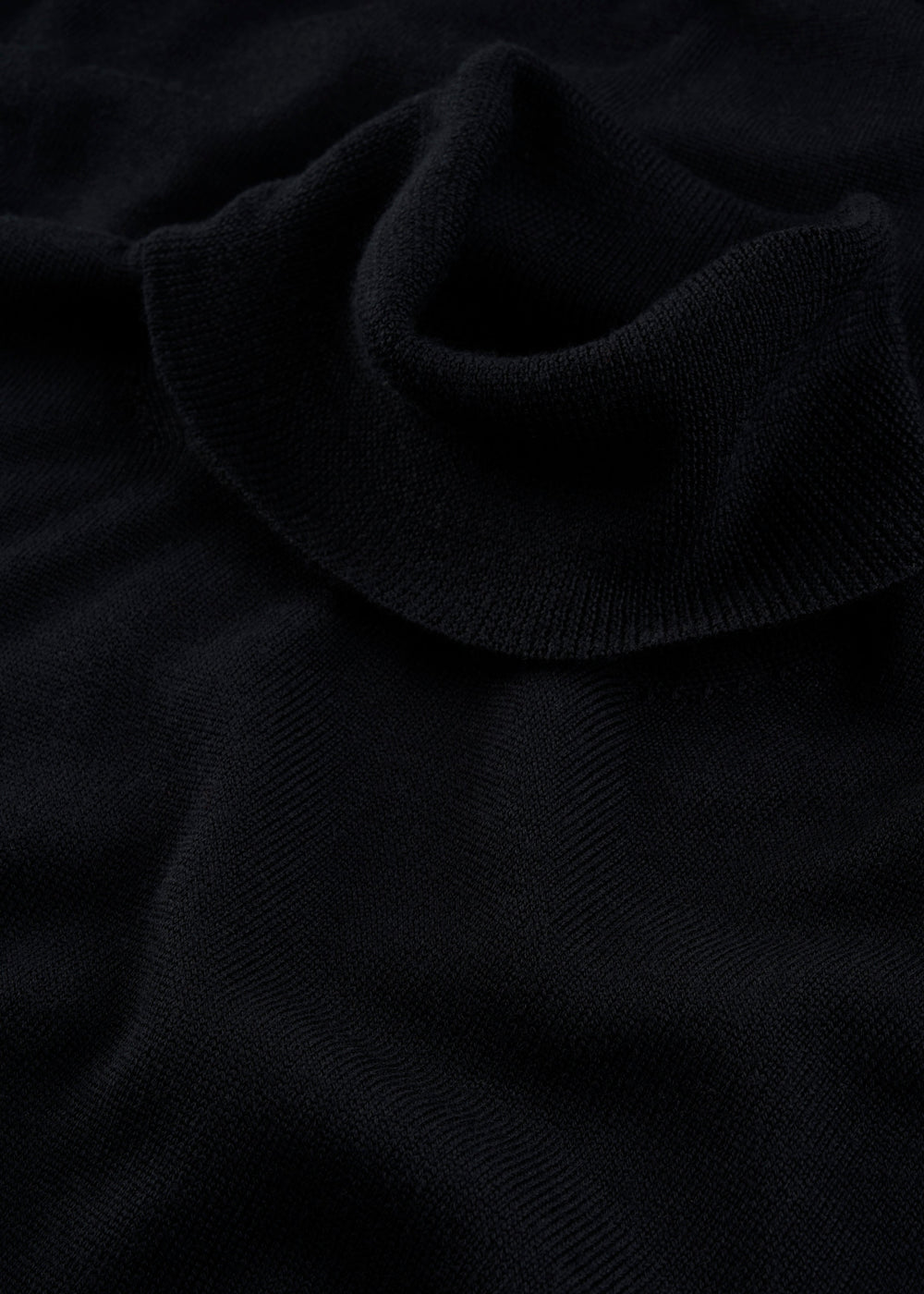 Close-up of the Linton Merino Wool Roll Neck Jumper in black, spotlighting its soft knit collar and stylish design.