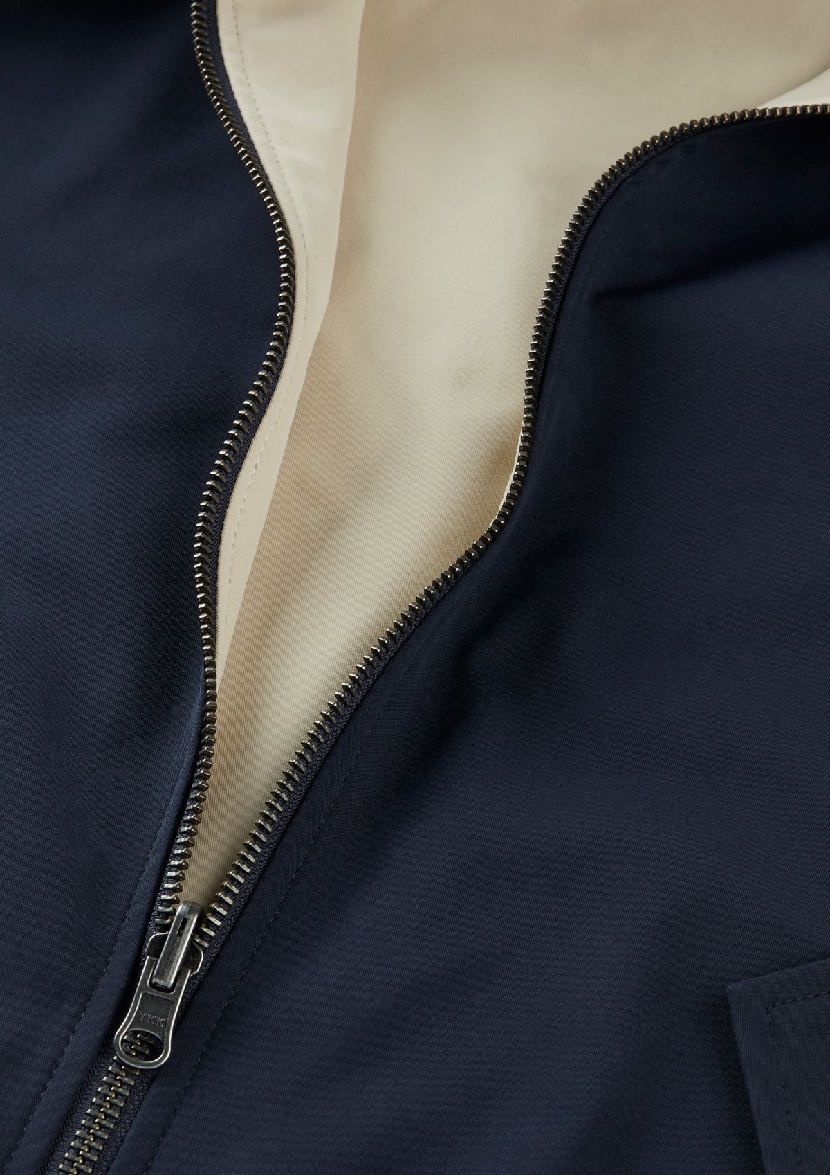 Close-up of Lakeward Men’s Reversible Bomber Jacket in navy with open silver zipper showing beige inner lining.