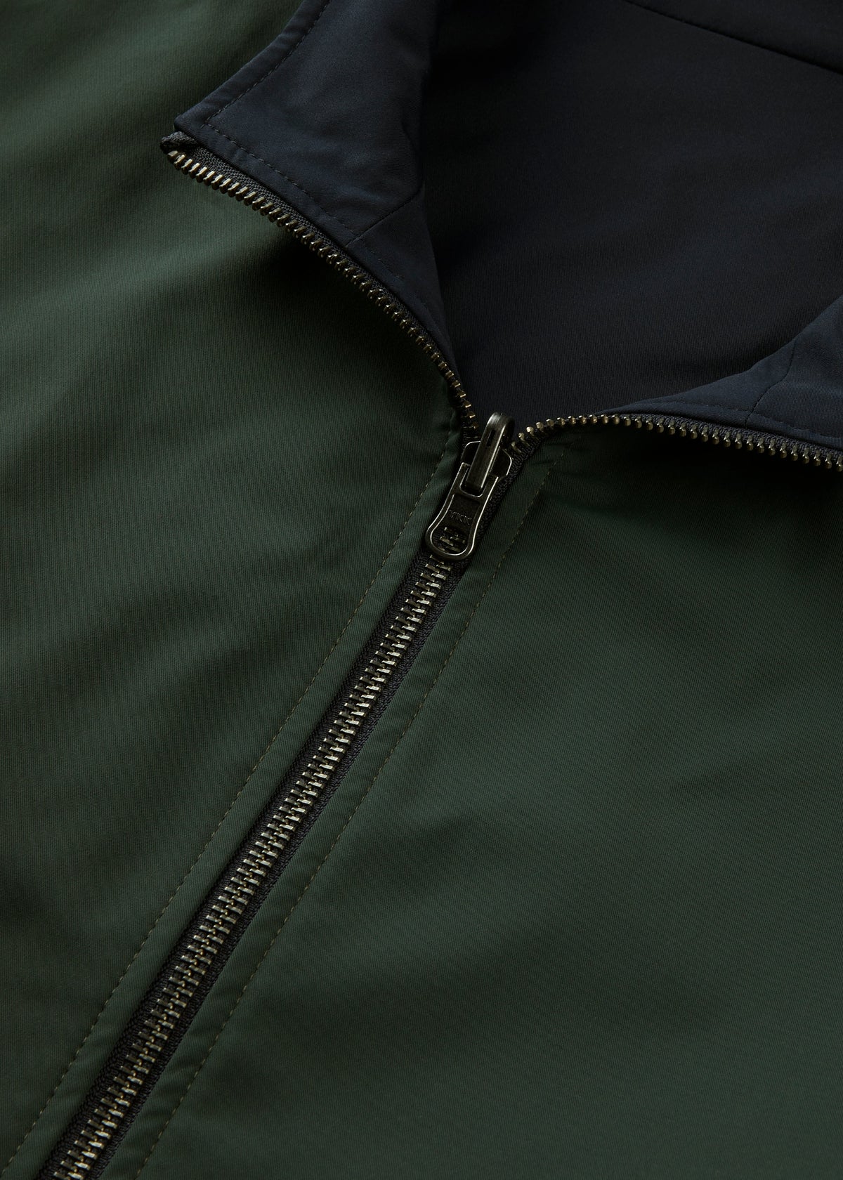 Close-up of the Lakeward Men’s Reversible Bomber Jacket in green and navy, features black lining and partial zipper.
