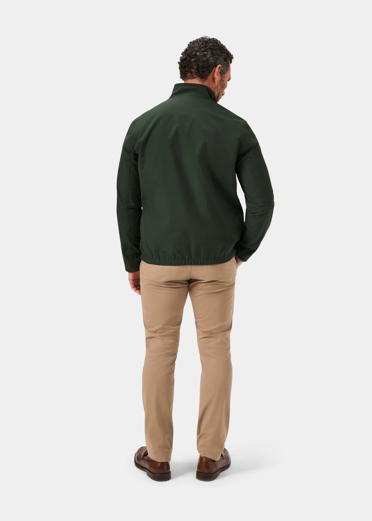 Man facing away, wearing Lakeward Men’s Reversible Bomber Jacket in Green and Navy, beige pants, and brown shoes.