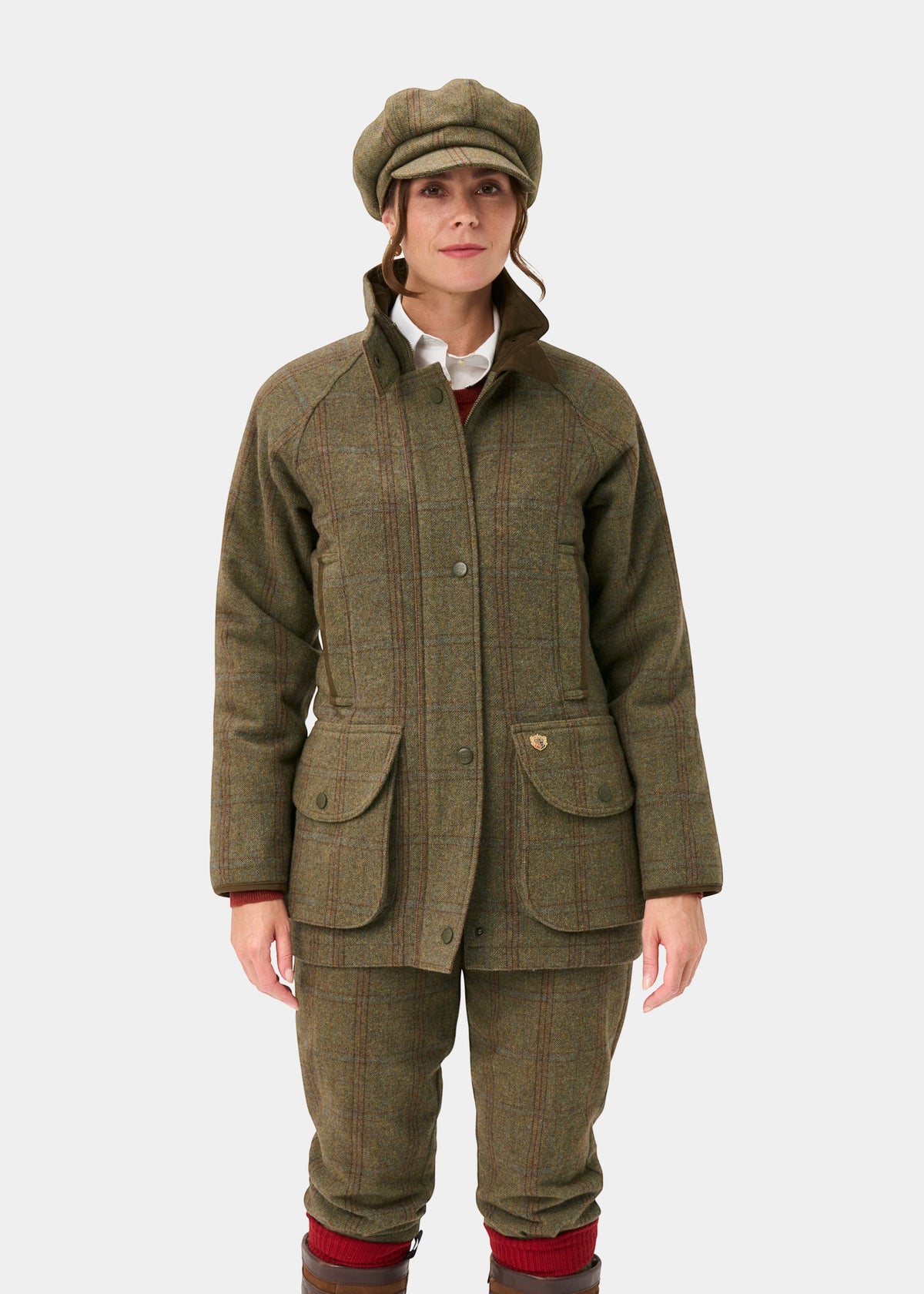 Woman in Combrook Ladies Tweed Waterproof Shooting Coat in Laurel, standing against a plain white background.