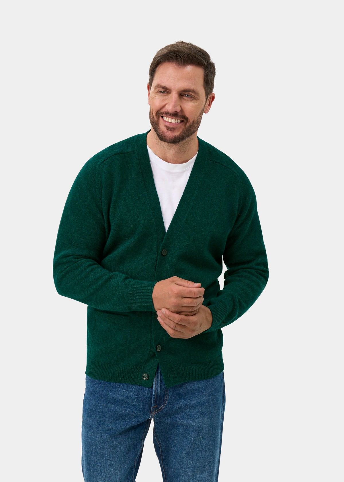 Man wearing Cornwall Lambswool V-Neck Cardigan in Mallard, white tee, and jeans stands against plain light background.