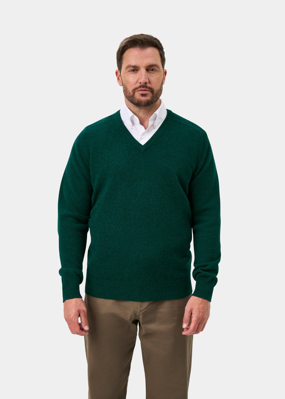 Man in Hampshire Lambswool V-Neck Jumper in Mallard, over white shirt & khaki pants, against light background.