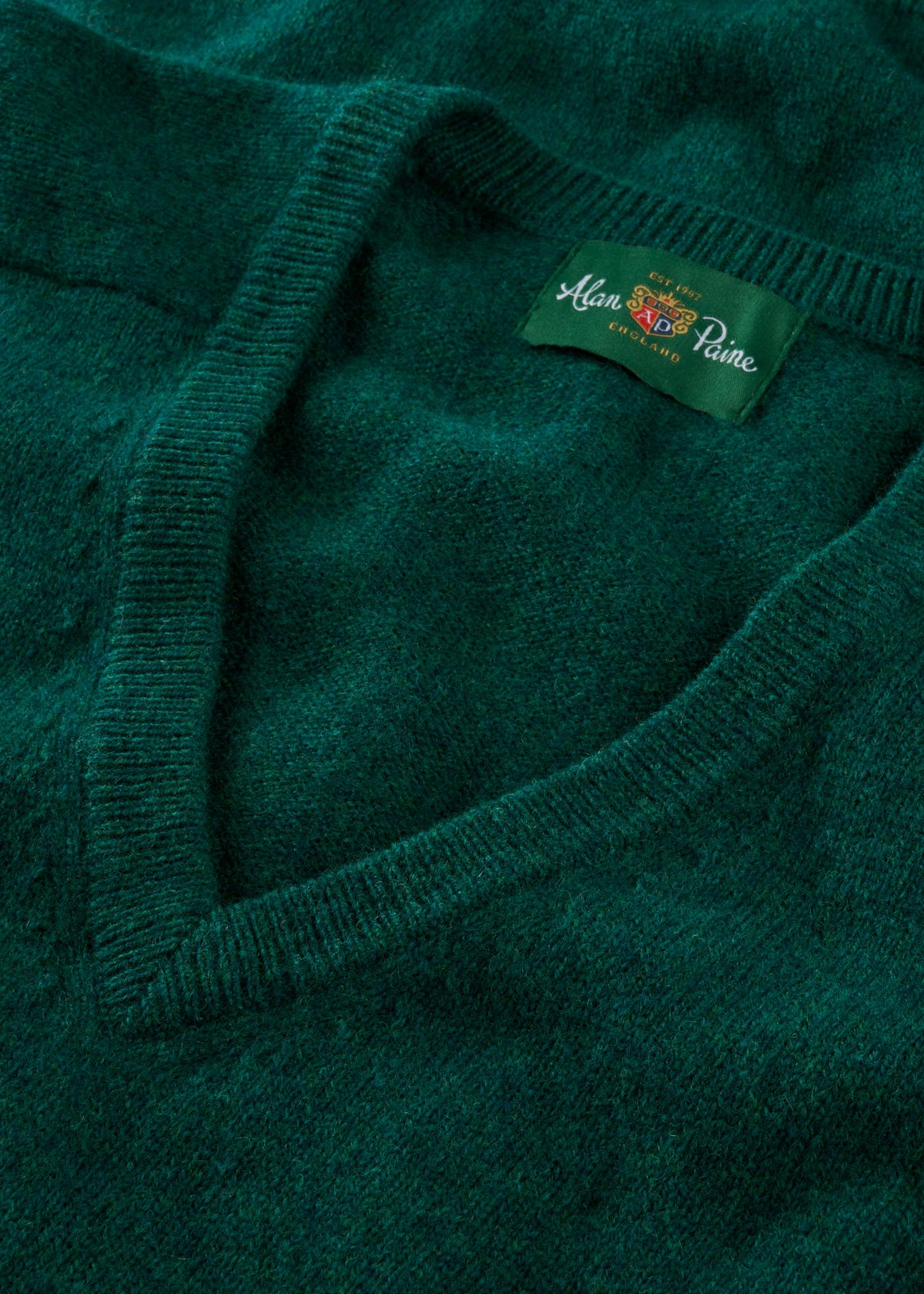 Close-up of Hampshire Lambswool V-Neck Jumper in Mallard, classic fit, featuring saddle shoulder and Alan Paine label.