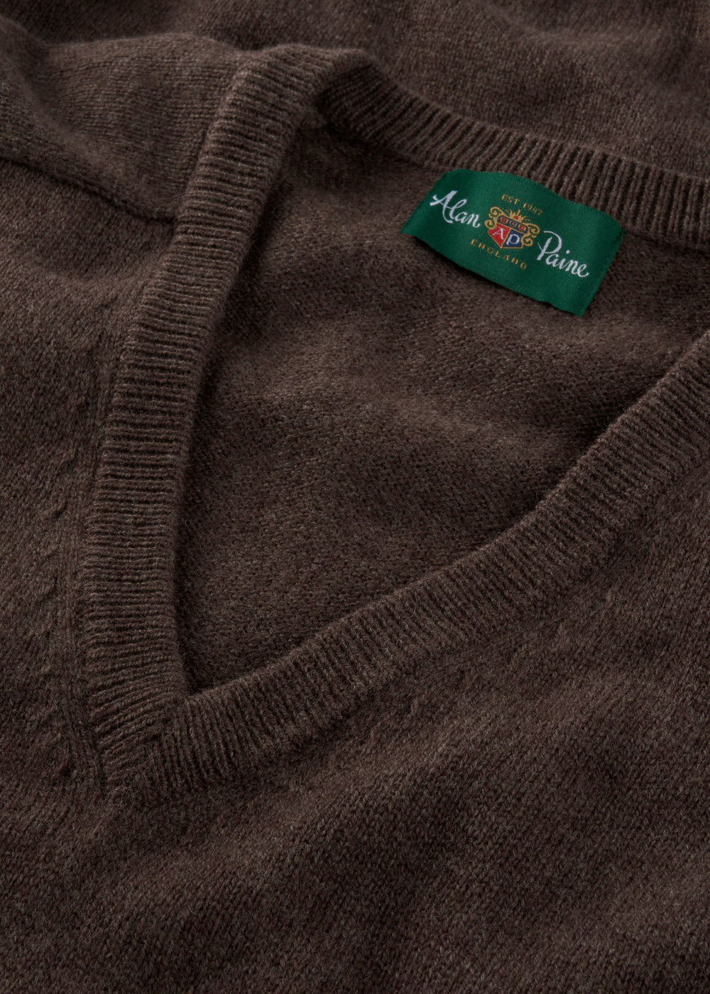 Close-up of the Hampshire Lambswool V-Neck Jumper in Mocha, classic fit, with visible green Alan Paine collar tag.