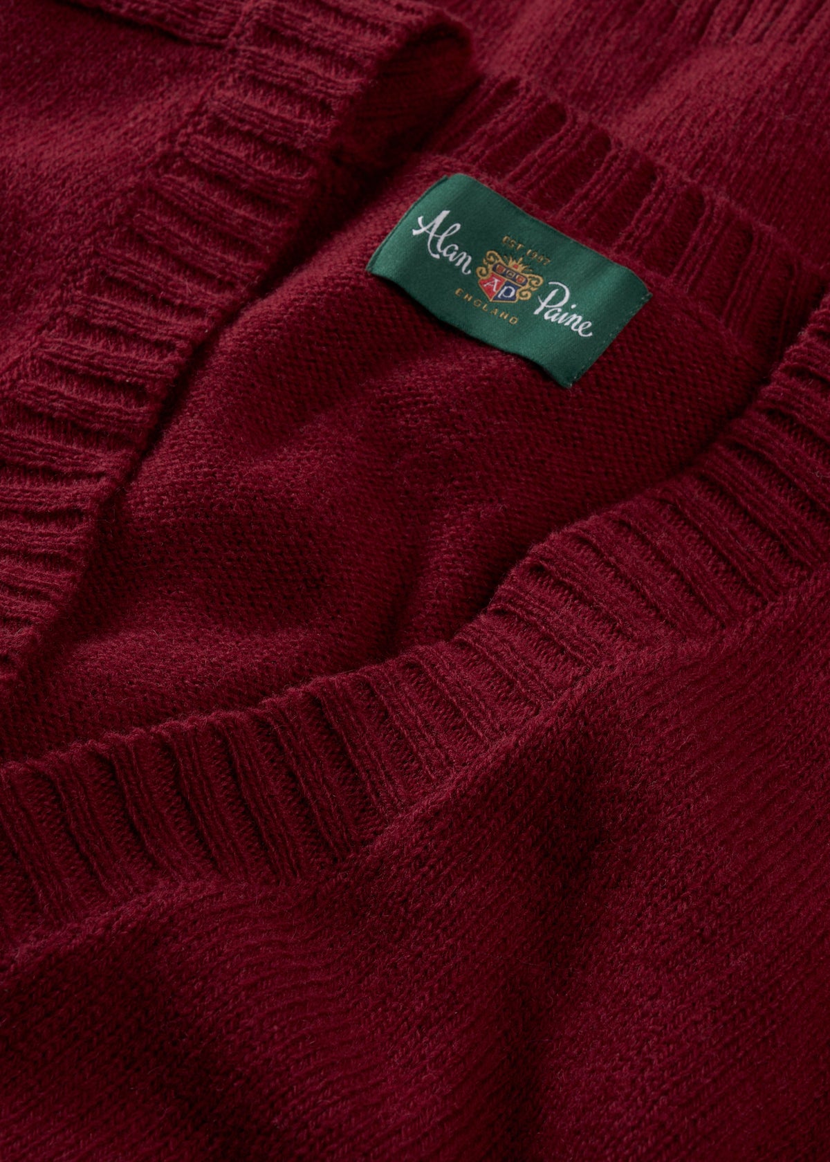 Close-up of a Kinloch Supersoft Shetland Wool V-Neck Cardigan in Venetian with a green Alan Paine label inside.