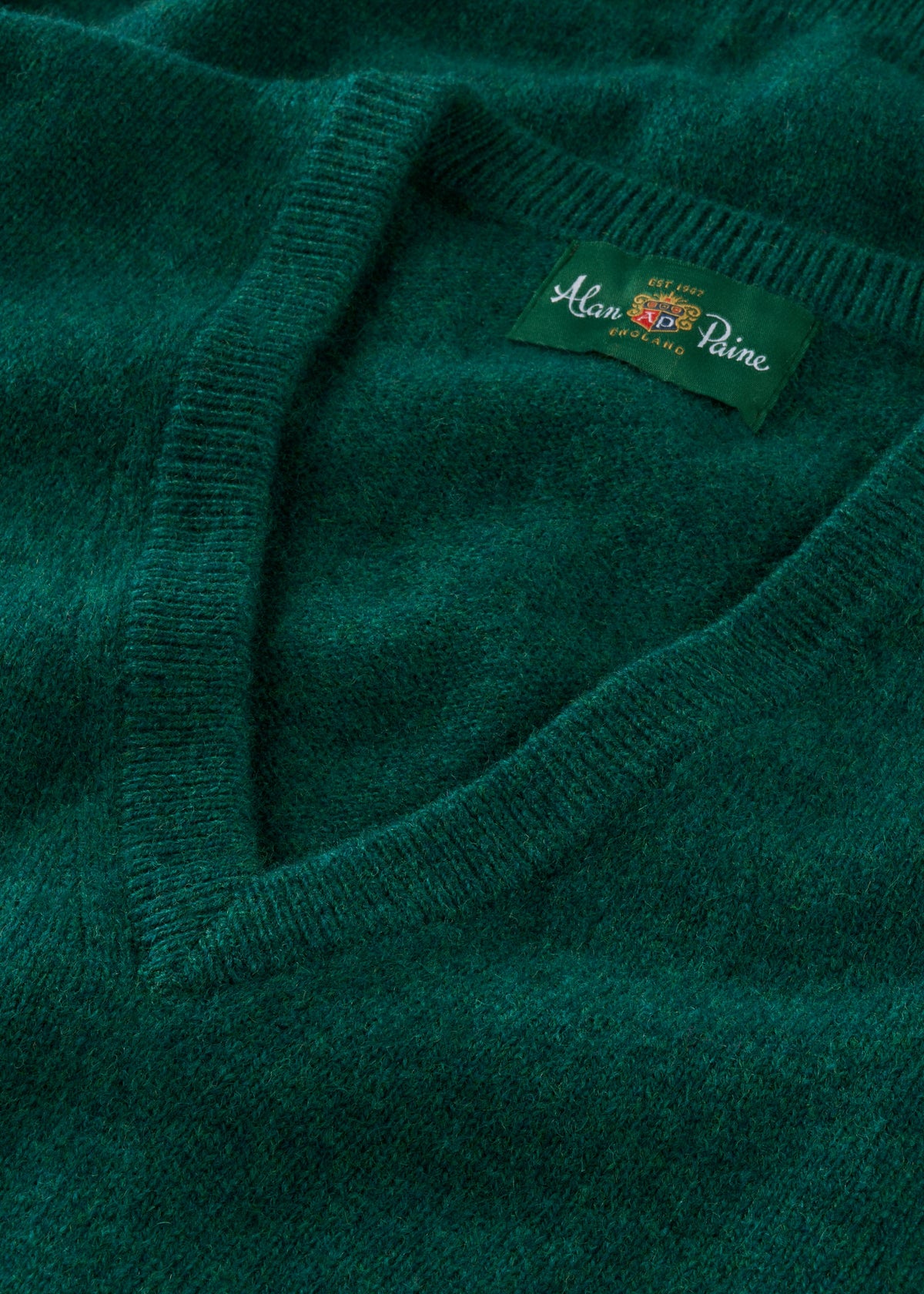 Close-up of a green sweater with a brand label on a matching background