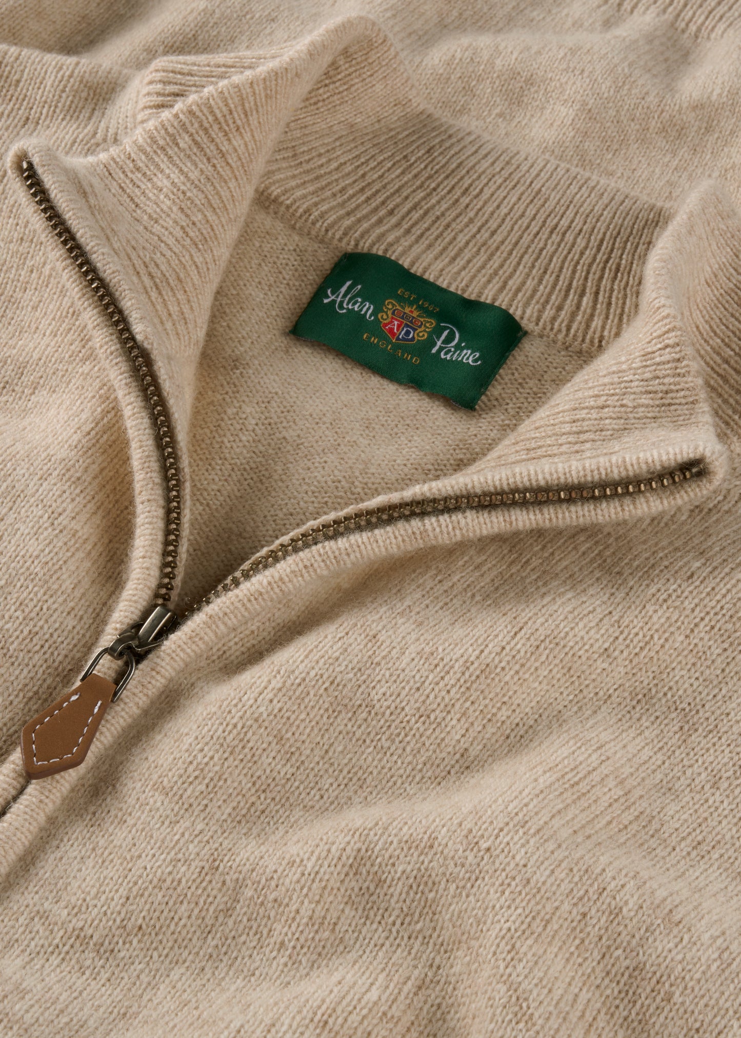 Close-up of a beige sweater with a brand label on the collar.